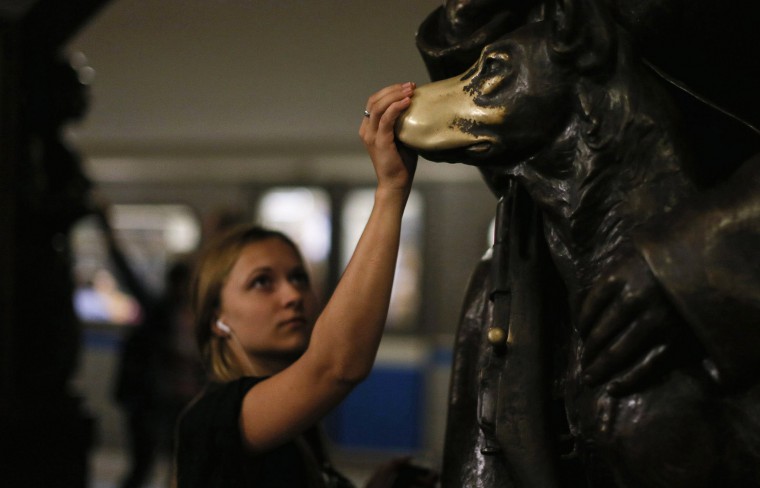 Woman touches nose of the "lucky dog" statue at the Ploshchad Revolyutsii Metro station in Moscow